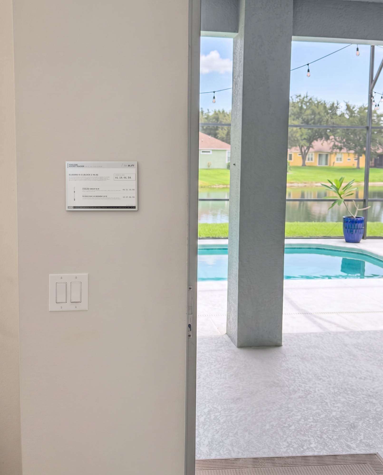 The Poolside Rocket Tracker mounted on an interior wall overlooking a screened pool and lake